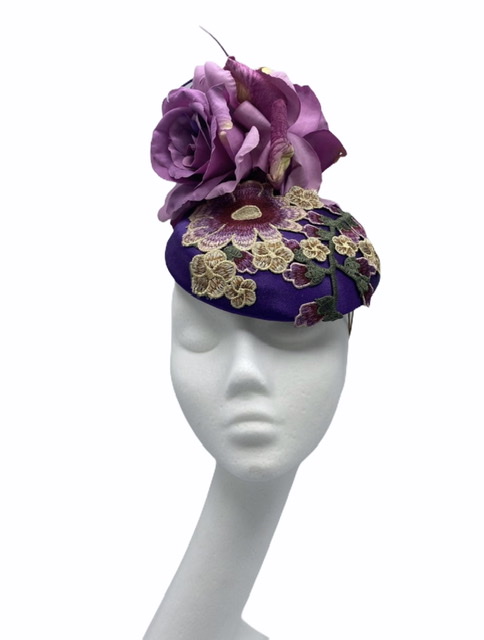 Purple headpiece with a beautiful embellished detail (yellow/green/pink) to the base, finished with pink flowers and pink quills.