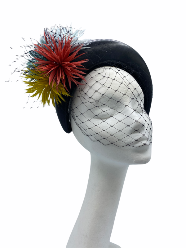 Black leather crown finished with mint/coral/yellow flower detail. Black veiling covers the face entirely.