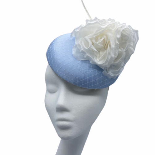 Baby blue satin pillbox with white netting finished with a white flower and white quill.