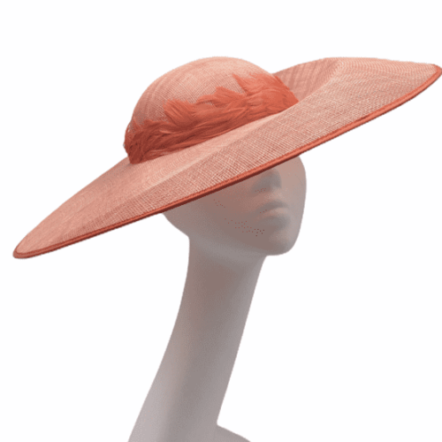 Large coral wide brim headpiece with feather trim detail to the topside.