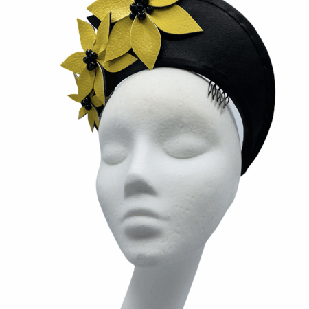 Black leather halo headpiece with yellow leather flowers to the right hand side with black pearl detail to the centre of each flower. There are 2 combs to secure this crown in place.