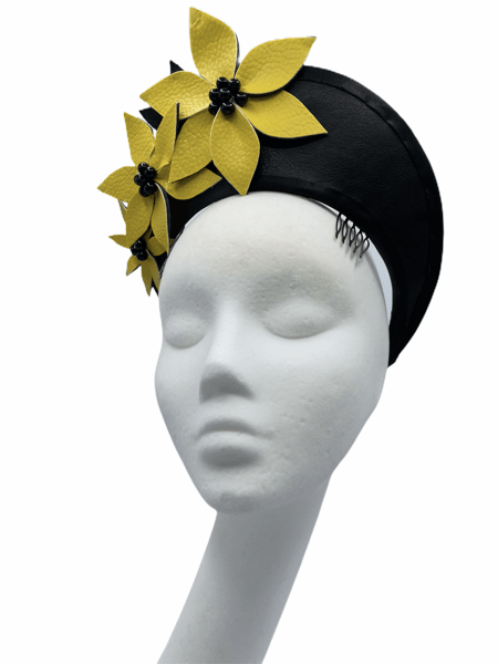 Black leather halo headpiece with yellow leather flowers to the right hand side with black pearl detail to the centre of each flower. There are 2 combs to secure this crown in place.