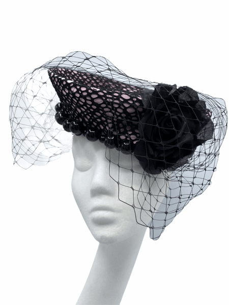 Stunning pink headpiece with black net overlay, encrusted with black bead detail. Finished in a beautiful black veiling.