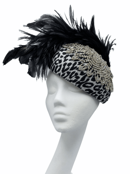 Black and white leopard print hat with large swarovski style detail to top with fab floaty feathers to the back.