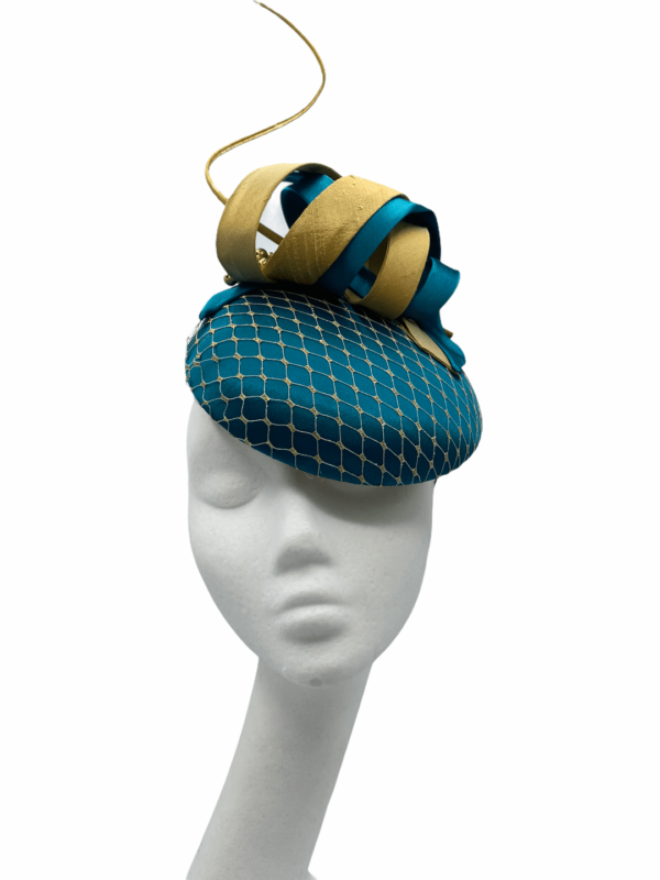 Teal coloured headpiece with gold netting overlay to the base and gold quill and swirl detail.