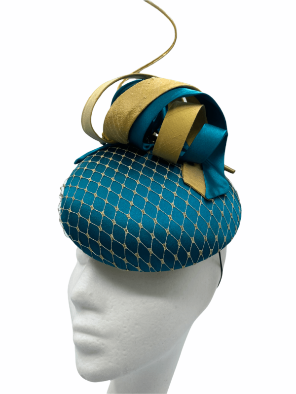 Teal coloured headpiece with gold netting overlay to the base and gold quill and swirl detail.