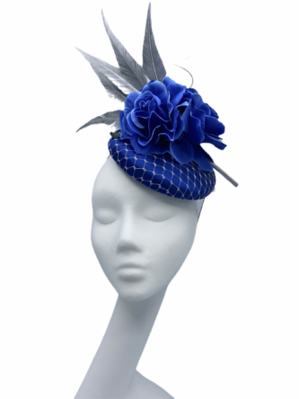 Blue pillbox headpiece with silver net overlay. The headpiece is finished with some silver arrow head feathers and flower detail.