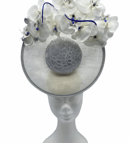 White centre percher headpiece with white/silver coloured lace overlay to the centre, finished with an array of white orchid flowers to the top with royal blue centre pearls and royal blue quills.
