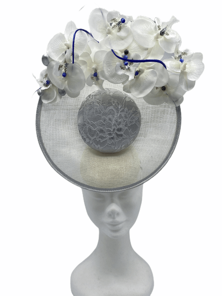 White centre percher headpiece with white/silver coloured lace overlay to the centre, finished with an array of white orchid flowers to the top with royal blue centre pearls and royal blue quills.