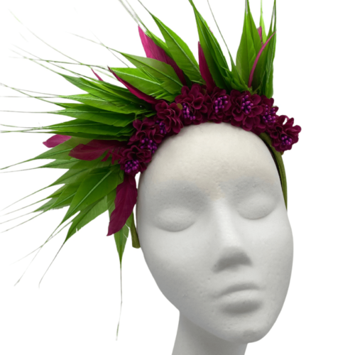Green/pink crown headpiece on a green silk headband. It has pink flowers to the centre with a spray of green/pink feathers. 