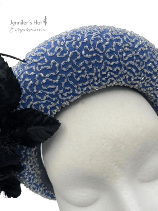 Stunning cornflower blue crown with hand beaded detail and black flower to one side.
