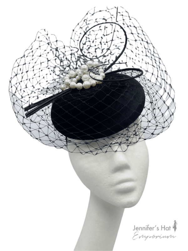 Black velvet headpiece with ruched veiling detail, finished with pearl detail and black quill. 
