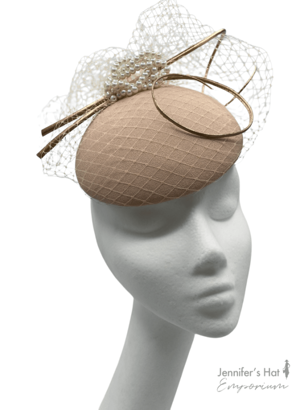 Nude coloured headpiece with ivory pearl detail,  finished with an ivory netting overlay and gold quill.