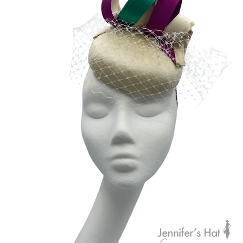 Cream coloured headpiece with veiling, finished with purple and green swirl detail.