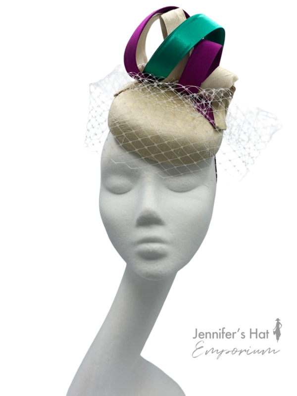 Cream coloured headpiece with veiling, finished with purple and green swirl detail.