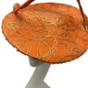 Orange saucer hat with large swirl detail with gold design detail overlay. 