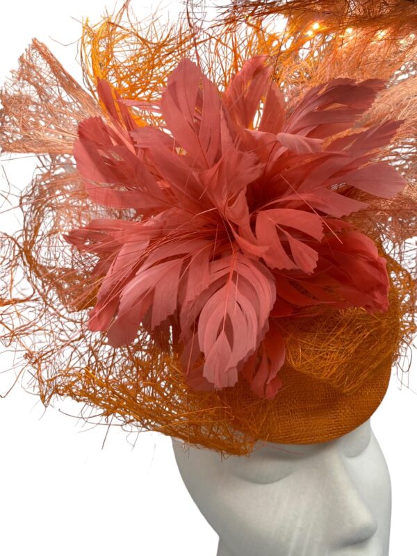 Large statement orange headpiece with a blush pink feather detail. 