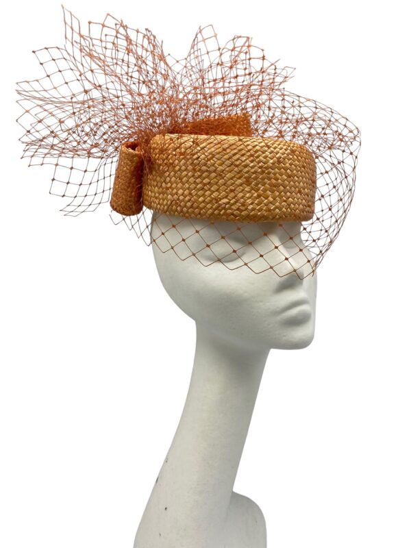 Orange veiled parasisal straw Jackie Onassis inspired headpiece with bow detail to the back.