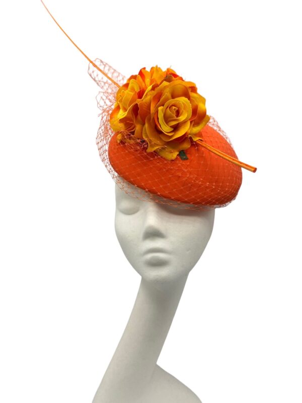 Orange coloured headpiece with orange net detailing all over with a gorgeous pop from the flower and finished with an orange quill.