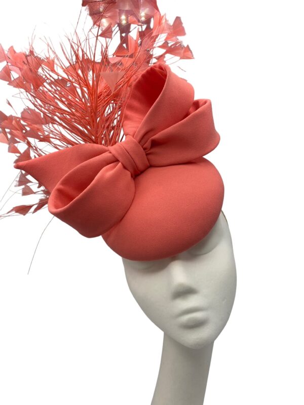 Coral headpiece with a spray of coral feathers and bow detail.