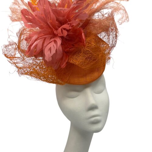Large statement orange headpiece with a blush pink feather detail. 