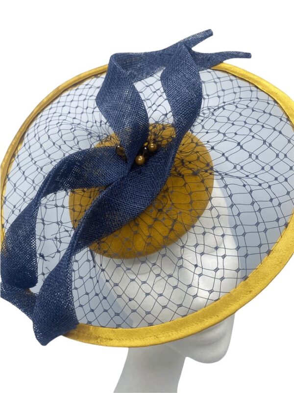 Mustard velvet headpiece with circular wire covered in mustard satin. Navy veiling over the entire headpiece with navy swirl detail.