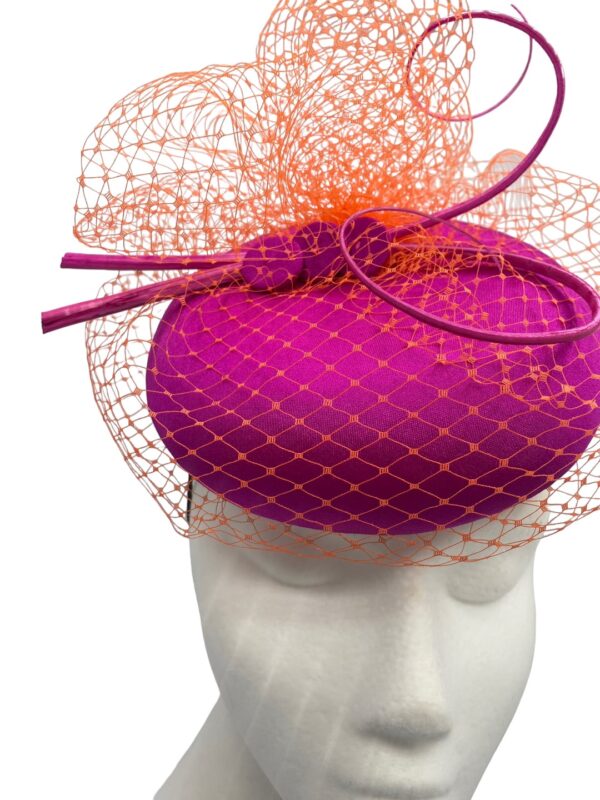 Gorgeous magenta pink headpiece with stunning orange veiling overlay with orange quill to finish.
