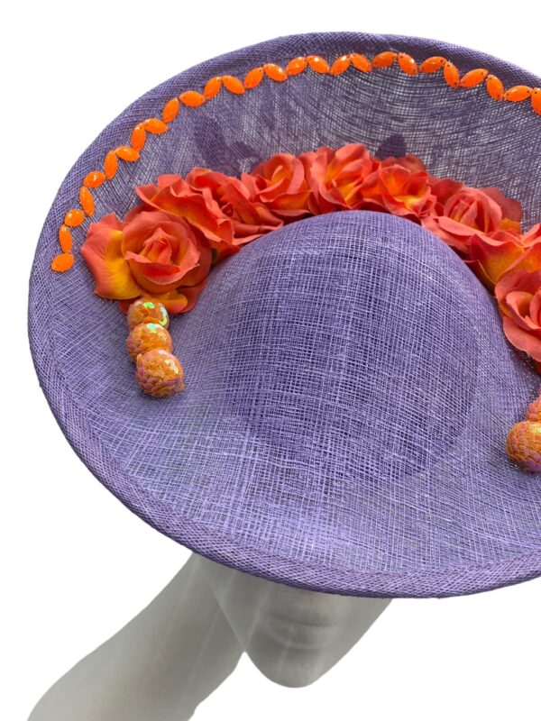 Lavender coloured centre saucer with an orange trim to the inside of the top of the headpiece, it has an array of orange/coral coloured flowers in a semi-circle and a some orange pearl detail to either end of semi-circle.
